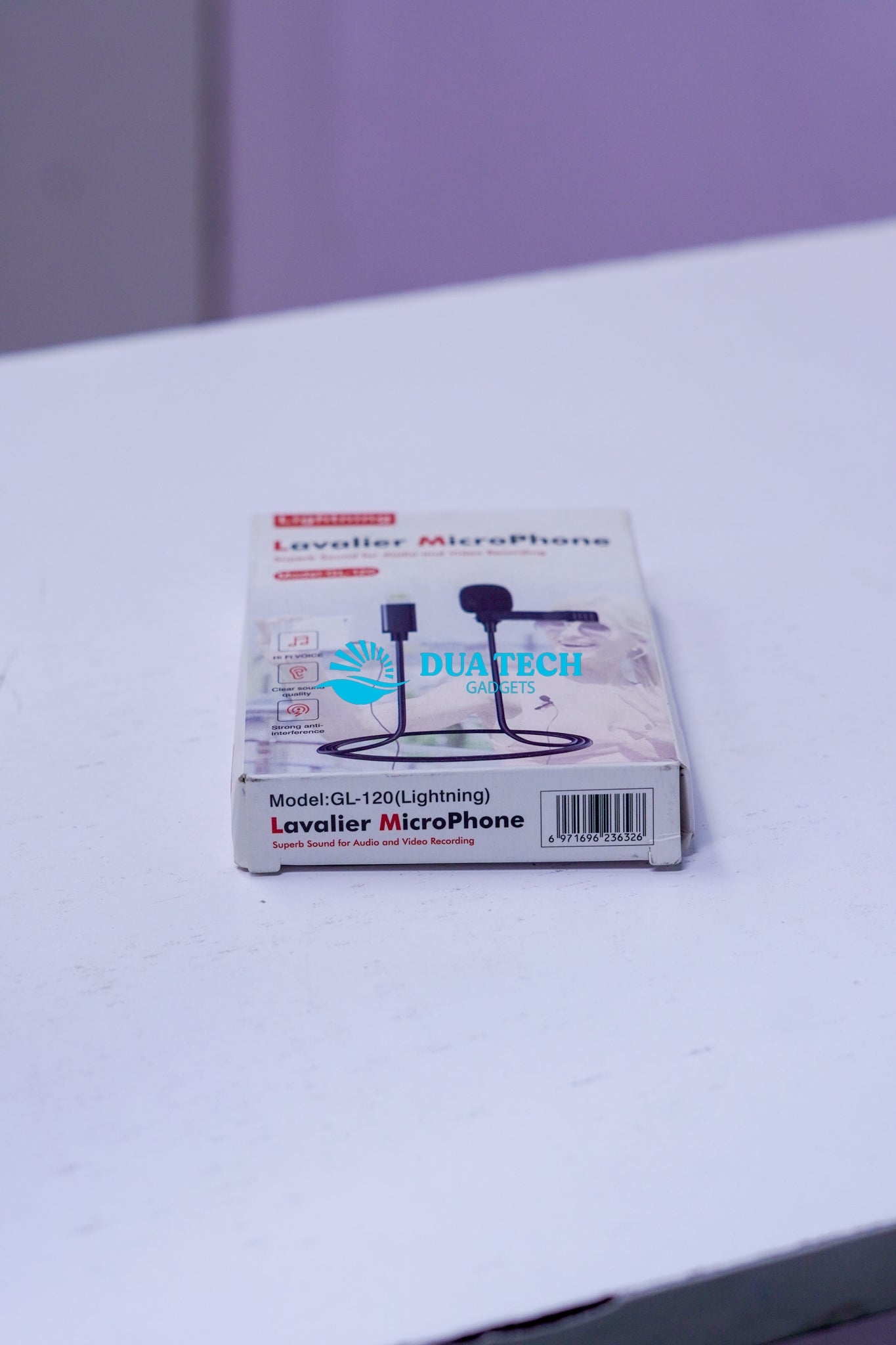 Box of a lavaliere microphone on a white surface with a purple background